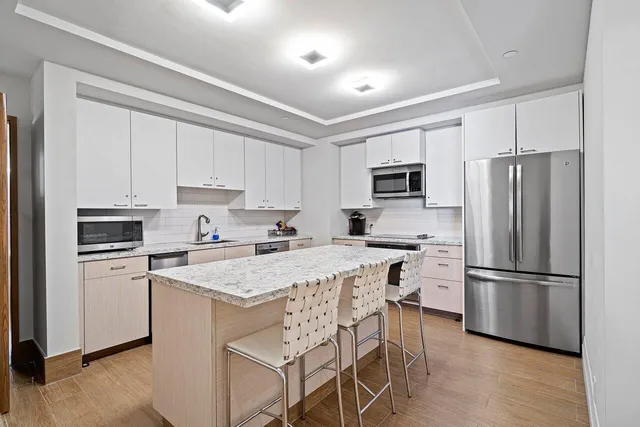 a kitchen with stainless steel appliances granite countertop a refrigerator stove microwave and white cabinets