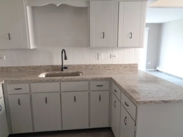 a kitchen with granite countertop white cabinets and a sink