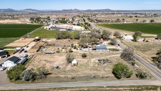 1211 West Midvalley Road Cedar City, UT 84721 - Photo 5 of 14 Expansive agricultural land featuring a verdant field, multiple outbuildings with dark roofs, and a large unpaved area