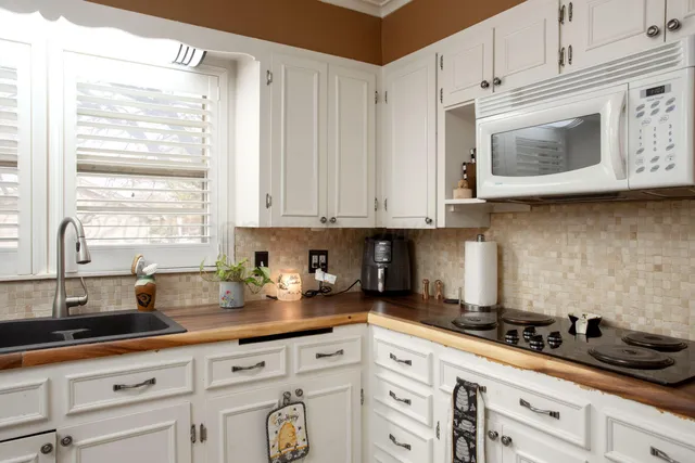 a kitchen with stainless steel appliances granite countertop white cabinets a window and a sink