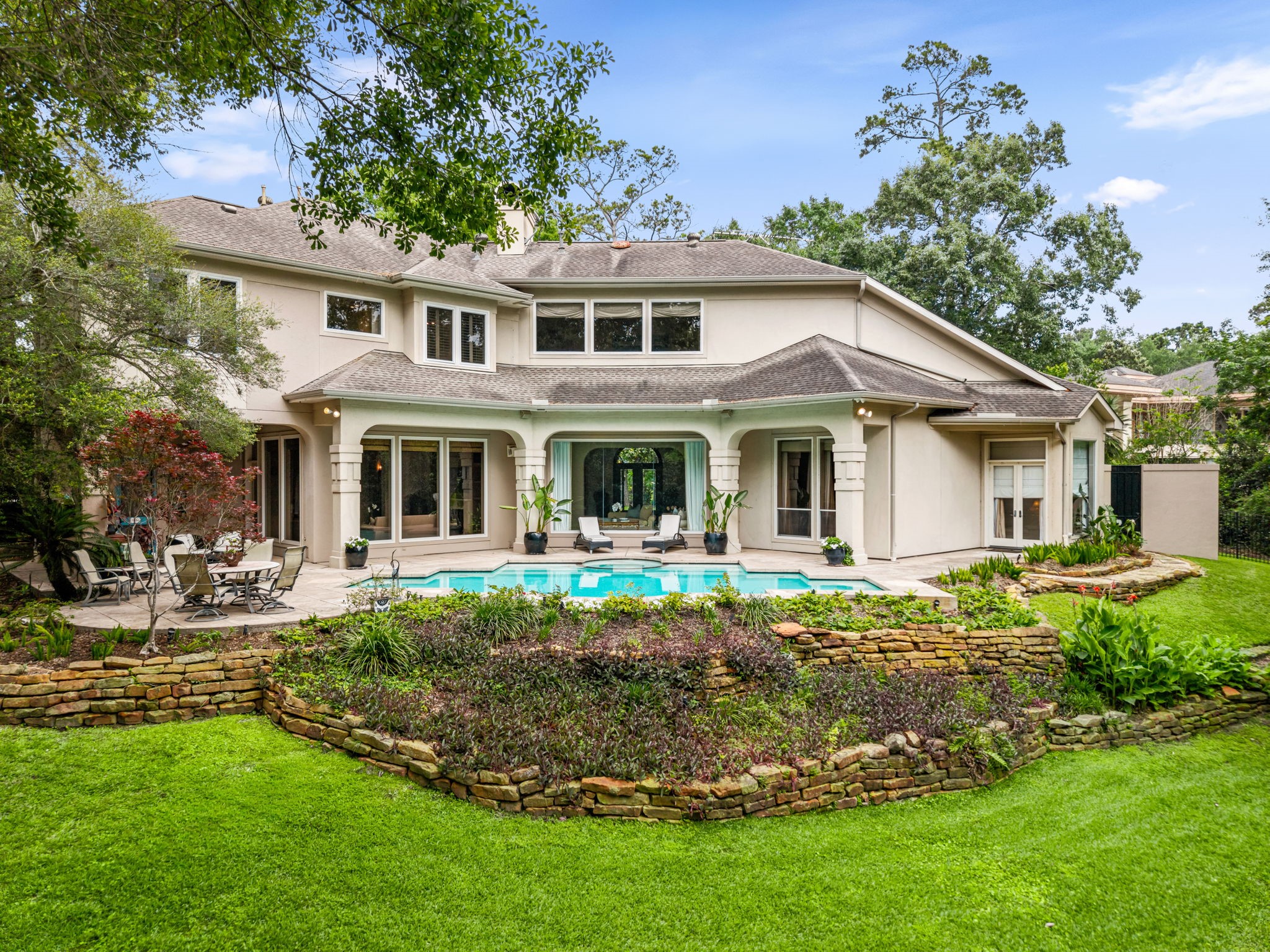 6 Mott Lane Houston, TX 77024 - Photo 46 of 50 Beautifully backyard retreat showcasing the home's elegant rear elevation, compete with a resort-style pool, multiple outdoor living areas, and lush, layered landscaping.