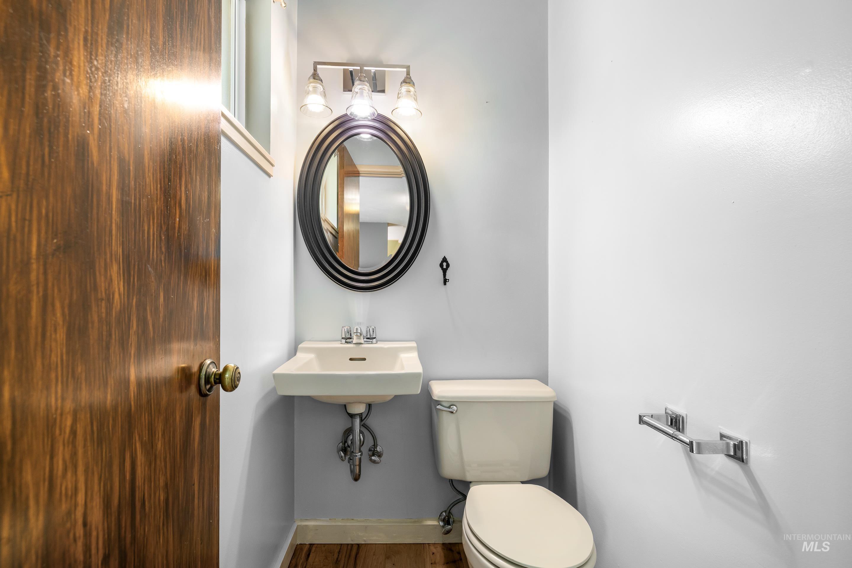 708 South Phillippi Street Boise, ID 83705 - Photo 18 of 25 Powder room featuring a wall-mounted sink, oval mirror with a decorative frame, and a three-light vanity fixture