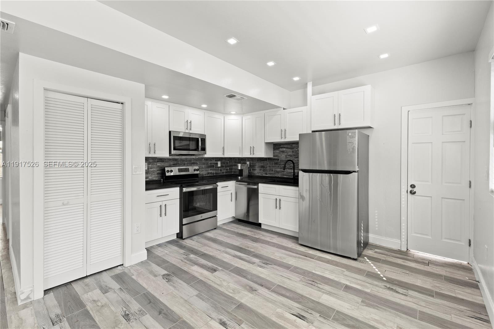 305 Northwest 58th Street Miami, FL 33127 - Photo 15 of 20 a kitchen with granite countertop white cabinets and stainless steel appliances