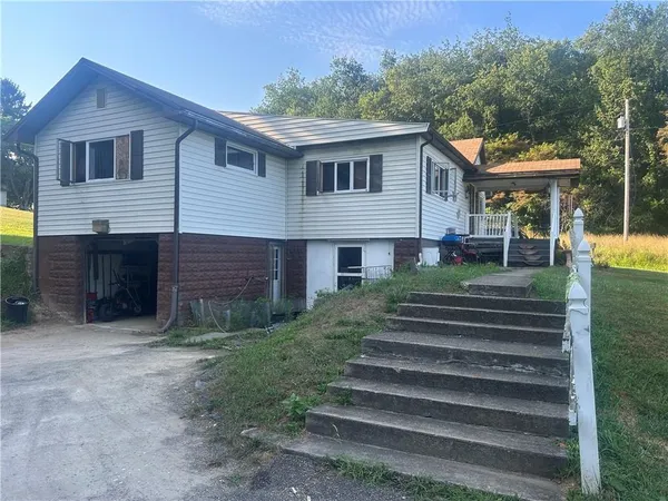 a front view of house with yard and trees in the background
