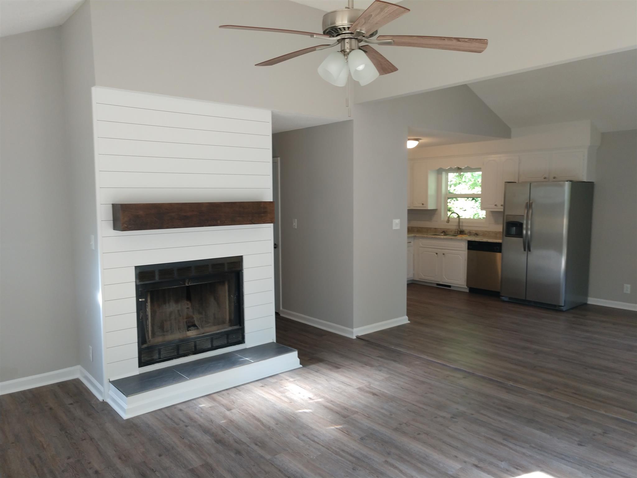 336 Harper Road Clarksville, TN 37043 - Photo 3 of 20 a view of a kitchen with a stove wooden floor a fireplace and a chandelier fan