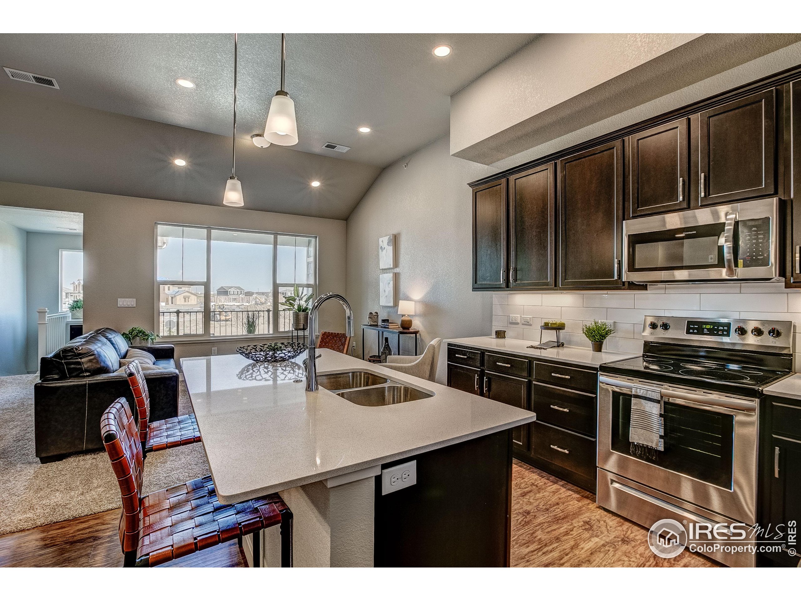 a kitchen with stainless steel appliances kitchen island granite countertop a stove a sink dishwasher a dining table and chairs with wooden cabinets