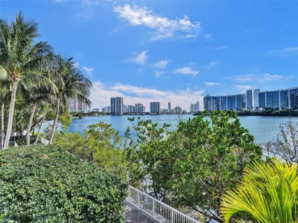 a view of a swimming pool with a lawn chairs and palm trees