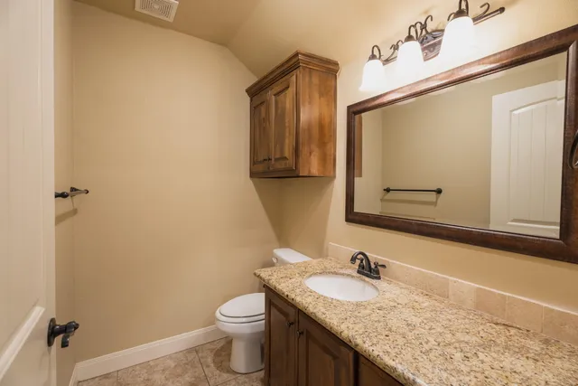 a bathroom with a granite countertop sink toilet and mirror