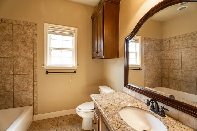 a bathroom with a granite countertop sink toilet and shower