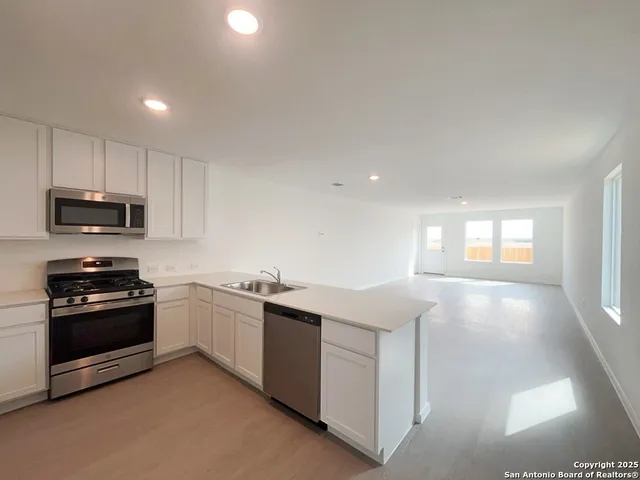 a kitchen with stainless steel appliances granite countertop a stove a sink and a microwave