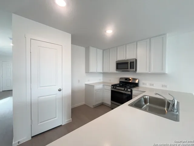 a kitchen with a sink white cabinets and stainless steel appliances