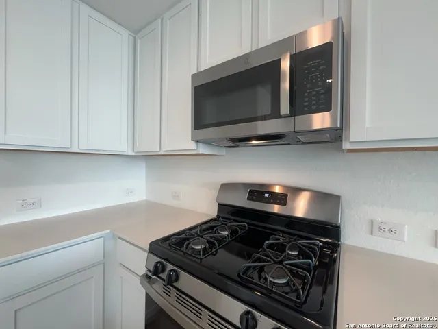 a kitchen with stainless steel appliances granite countertop white cabinets and a stove top oven