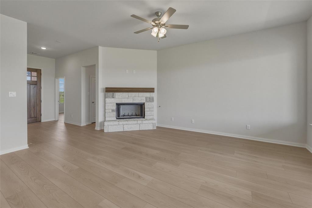 136 Hillview Trail Decatur, TX 76234 - Photo 10 of 26 Spacious living area featuring wood-finish flooring, a stone-surround fireplace with wood mantel, and a ceiling fan