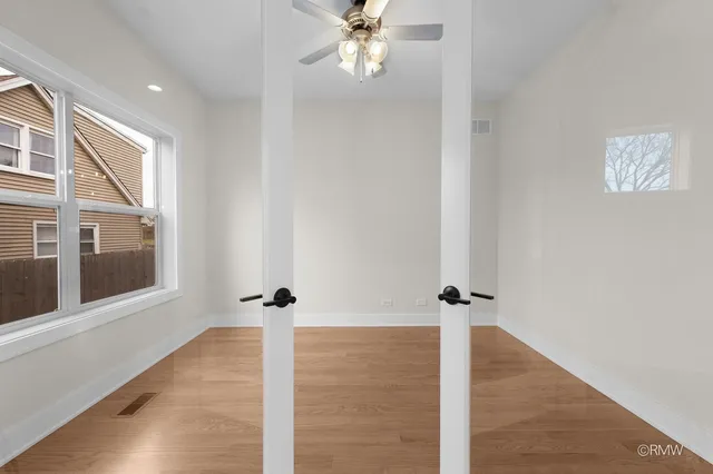 a view of a hallway with wooden floor and a ceiling fan