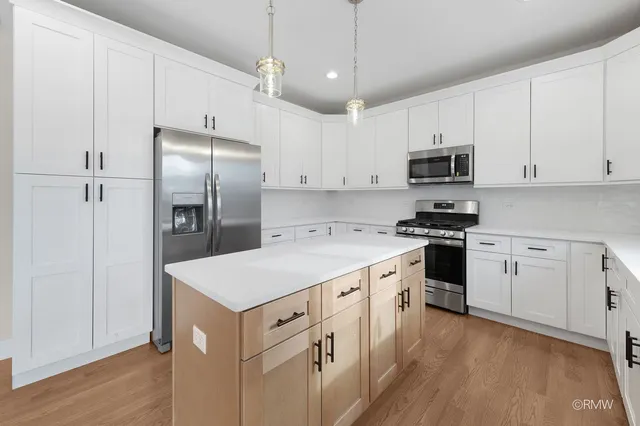 a kitchen with stainless steel appliances a refrigerator sink and white cabinets