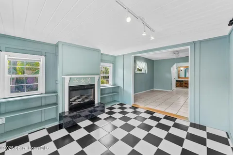 a living room with a black white checkered floor with a fireplace and a rug