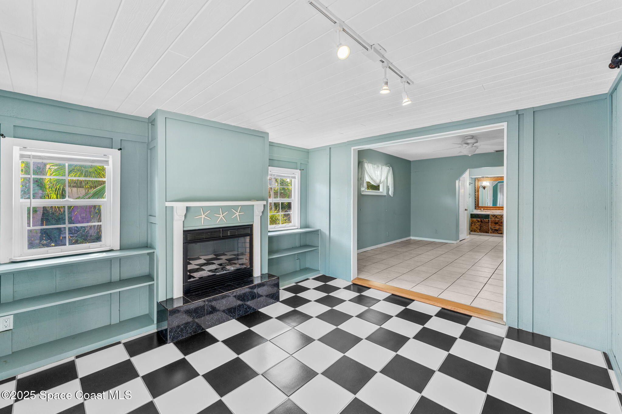 544 Solitaire Palm Drive Indialantic, FL 32903 - Photo 14 of 37 a living room with a black white checkered floor with a fireplace and a rug