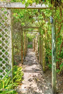 a view of yellow house with a yard and potted plants
