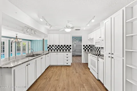 a large white kitchen with a lot of counter space and wooden floor