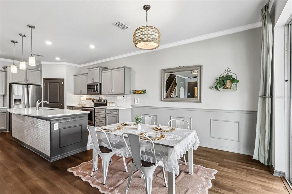 2575 Auburn Ridge Drive Apopka, FL 32712 - Photo 12 of 48 a kitchen with stainless steel appliances granite countertop a stove a refrigerator a microwave oven a dining table and chairs with wooden floor