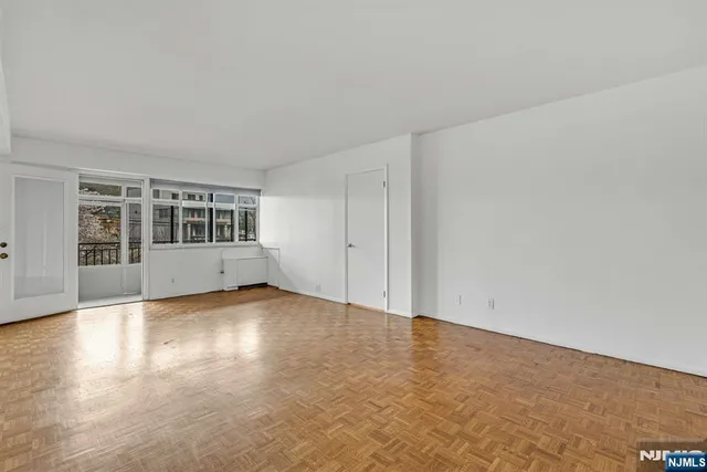 a view of an empty room with a window and wooden floor