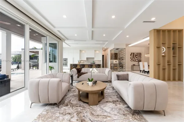 a living room with furniture kitchen view and a large window