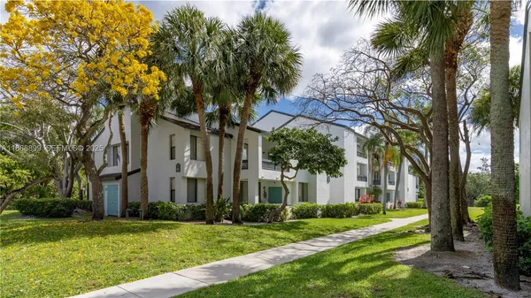 a view of a white house next to a yard and palm trees