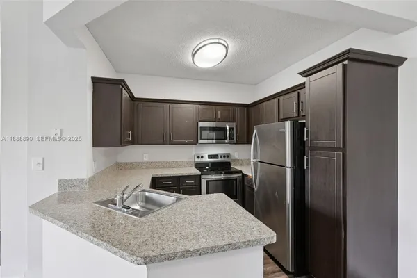 a kitchen with kitchen island a counter top space cabinets and stainless steel appliances
