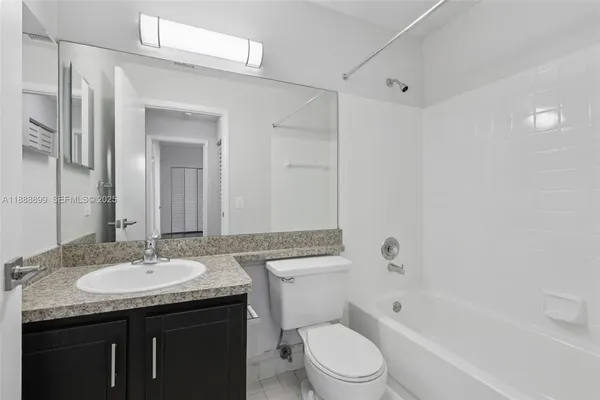 a bathroom with a granite countertop sink a mirror a toilet and bathtub