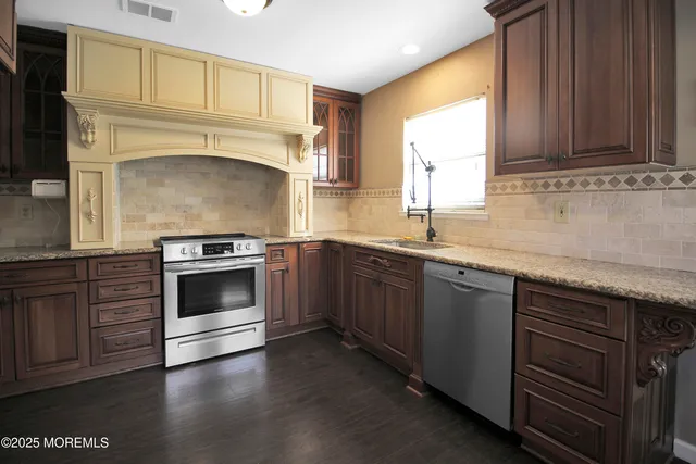 a kitchen with granite countertop a stove sink and cabinets