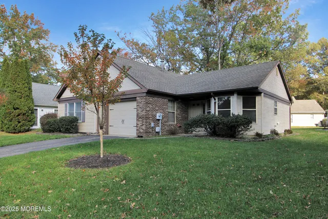 a view of a house with a yard plants and large tree
