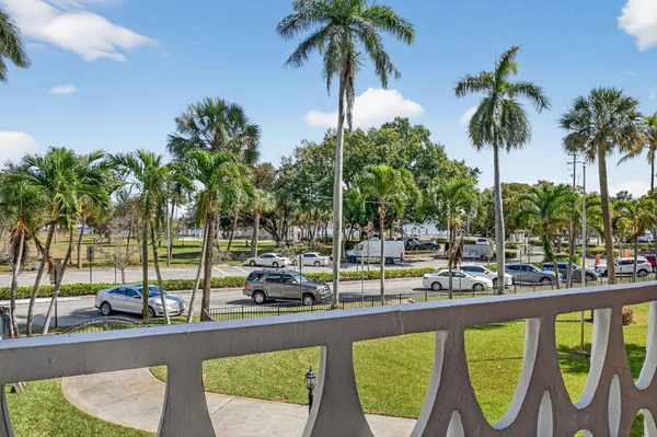 a view of a swimming pool with a lawn chairs under palm trees