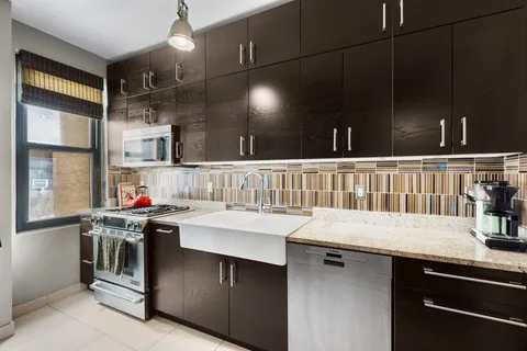 a kitchen that has a lot of cabinets in it and wooden floor