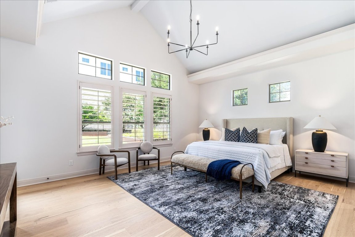 213 Black Wolf Run Austin, TX 78738 - Photo 12 of 39 a spacious bedroom with a bed a chandelier and a window