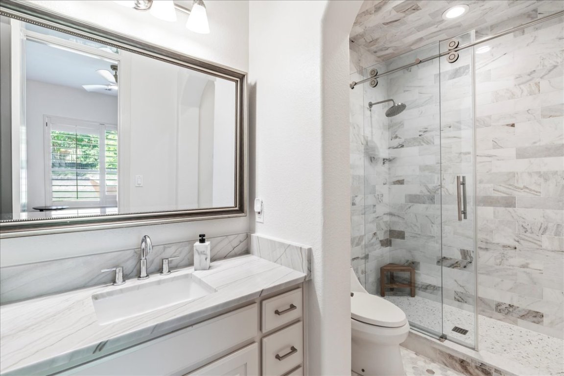 213 Black Wolf Run Austin, TX 78738 - Photo 22 of 39 a bathroom with a granite countertop sink toilet a mirror and shower