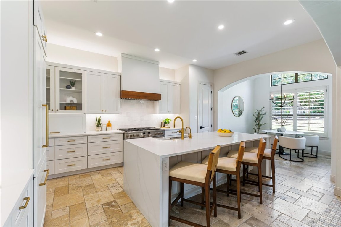 213 Black Wolf Run Austin, TX 78738 - Photo 9 of 39 a kitchen with stainless steel appliances granite countertop a stove a sink a dining table and chairs
