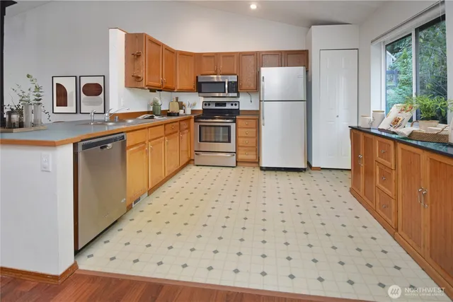 a kitchen with stainless steel appliances granite countertop a stove a refrigerator a kitchen island a dining table and chairs with wooden floor