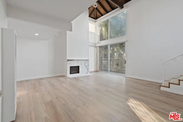 a view of an empty room with wooden floor fireplace and a window
