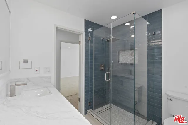 a bathroom with a granite countertop sink a toilet and shower