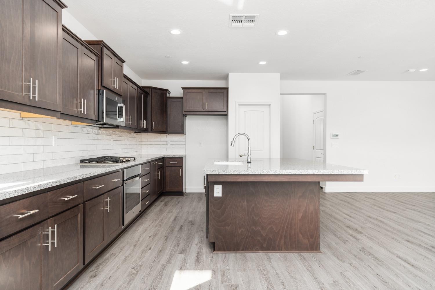 321 Peters Road Madera, CA 93636 - Photo 23 of 33 a kitchen with stainless steel appliances granite countertop a sink a stove and a wooden floors