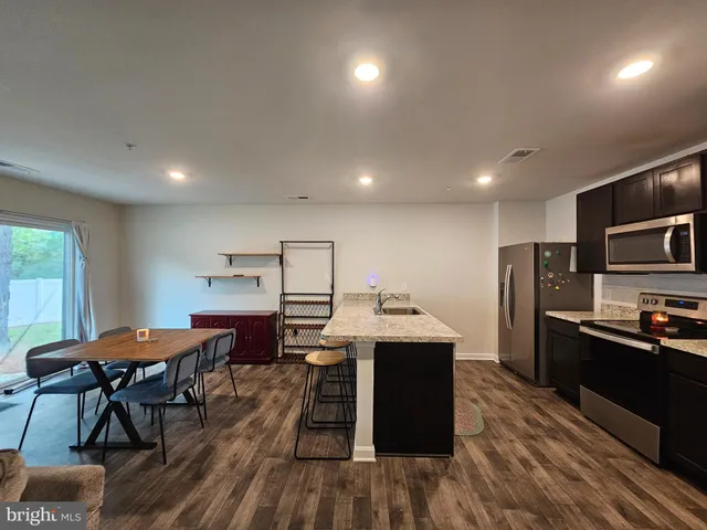 a kitchen with stainless steel appliances kitchen island granite countertop a table chairs and a refrigerator