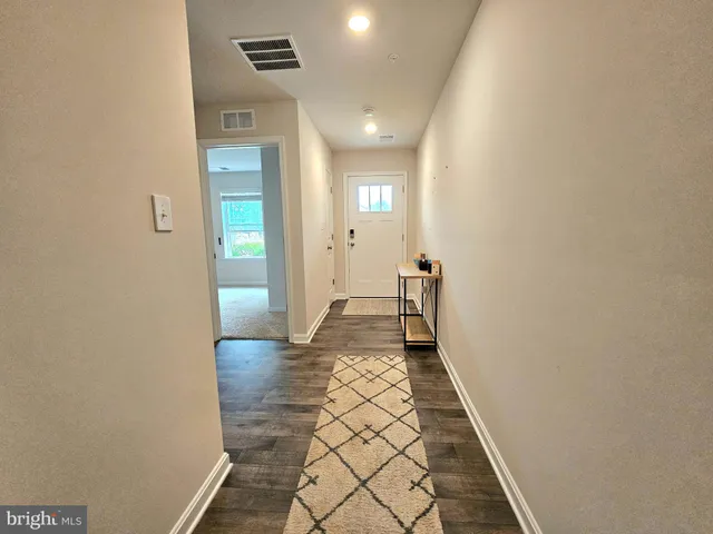 a view of a hallway with wooden floor and a bathroom