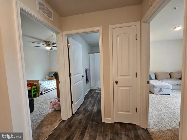 a view of a hallway with wooden floor and a living room