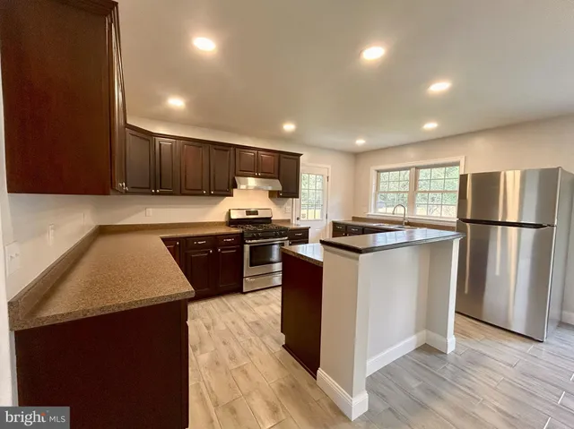 a kitchen with stainless steel appliances granite countertop a refrigerator a sink dishwasher a stove and a refrigerator with wooden floor