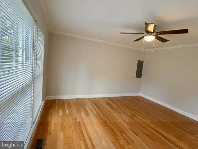 an empty room with wooden floor fan and windows