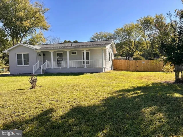 a view of a house with a yard and large tree