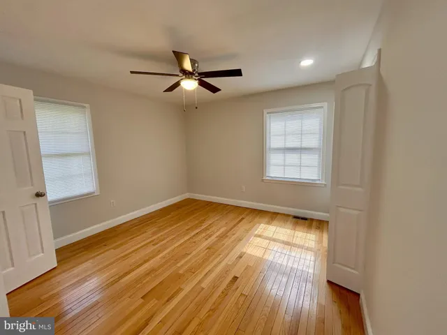 a view of empty room with wooden floor and fan