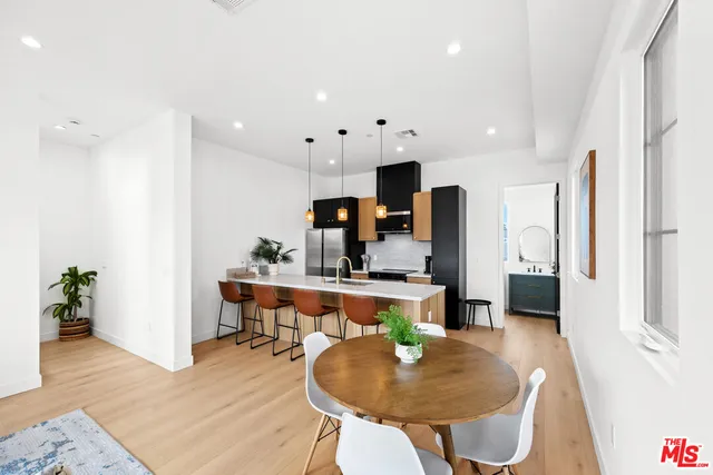 a living room with furniture a wooden floor and kitchen view