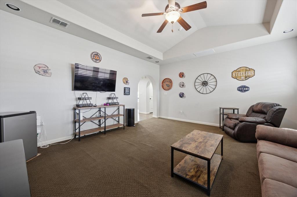 580 Butchart Drive Prosper, TX 75078 - Photo 23 of 40 Living room featuring arched walkways, ceiling fan, dark carpet, lofted ceiling, and baseboards