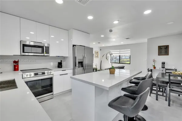 a open kitchen with stainless steel appliances kitchen island granite countertop a stove a sink a dining table and chairs